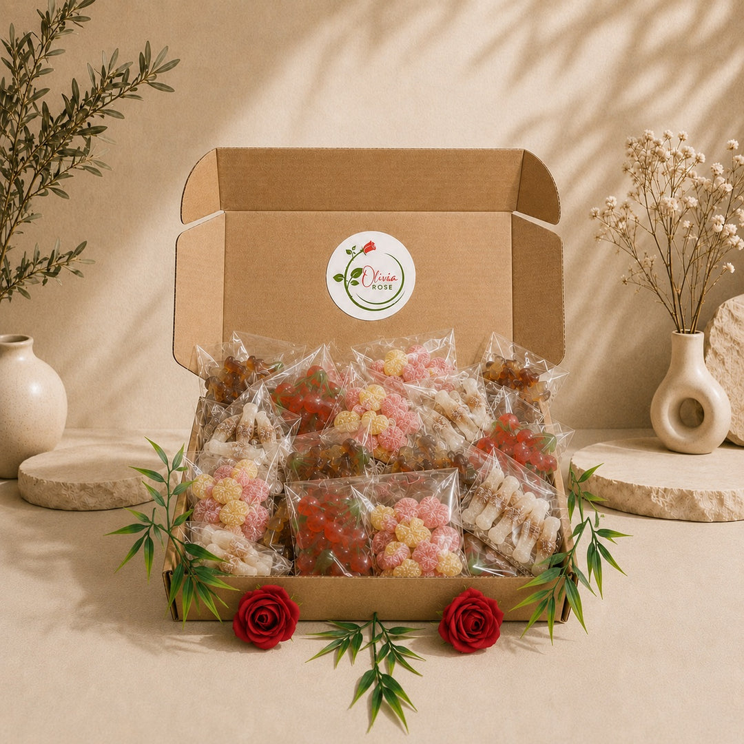 An open kraft cardboard gift box filled with individually wrapped gummy sweets and rose decoration, displayed on a beige surface with decorative vases and dried flowers in the background.